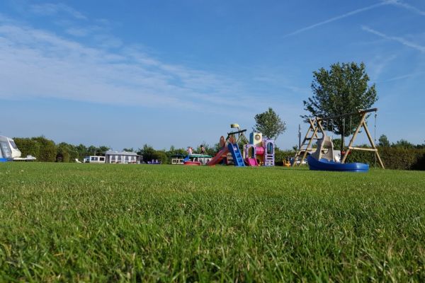 Speeltoestellen die staan op een grasveld op onze camping in de omgeving van Breda. 